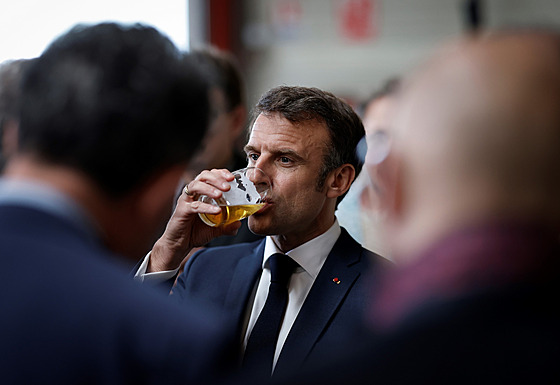 Francouzský prezident Emmanuel Macron pije pivo během návštěvy společnosti...