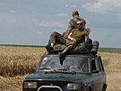 Ukrajintí vojáci jedou na stee auta po silnici poblí nedávno dobyté vesnice...