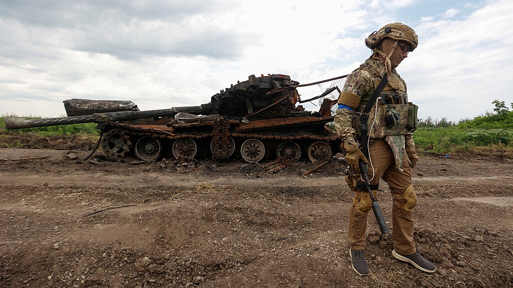 Ukrajinský voják kráí vedle znieného ruského tanku v nedávno dobyté vesnici...