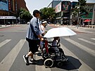 Chodci pecházejí silnici v horkém dni v Pekingu. (16. ervna 2023)