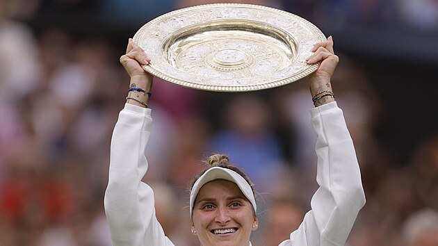 Markéta Vondroušová zvedá trofej pro vítězku Wimbledonu.