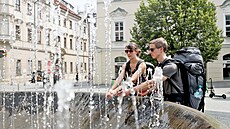 Lidé se chladí u kašny v centru Brna. (10. července 2023)
