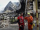 Ukrajintí hasii a záchranái pracují na míst zniené budovy po ruském...