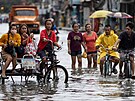 Lidé se brodí zaplavenou ulicí po tajfunu Doksuri ve Valenzuele na Filipínách....