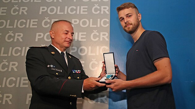 Ostravsk� policejn� �editel Anton�n �ezn��ek p�ed�v� medaili za state�nost 24let�mu Eduardovi Ra�n�mu, kter� zadr�el dva recidivisty okr�daj�c� seniora. (26. �ervence 2023)