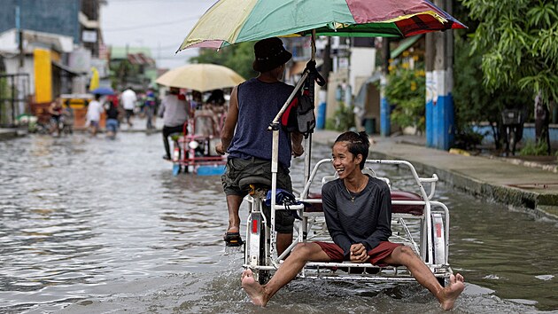 Lid se brod zaplavenou ulic po tajfunu Doksuri ve Valenzuele na Filipnch. (27. ervence 2023)