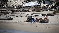 Dvojice leží pod slunečníkem na pláži na Rhodosu, kterou zasáhl požár. (26....