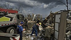 Ukrajintí záchranái a hasii pracují na míst zniené budovy po ruském útoku...