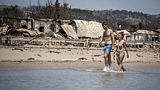 Dvojice se prochází na pláži na Rhodosu, kterou zasáhl požár. (26. července...