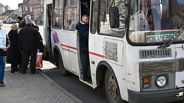 Mstn Ukrajinci i Maai nastupuj do autobusu pobl hlavnho nmst v Mukaevu na zpad Ukrajiny. (3. bezna 2023)