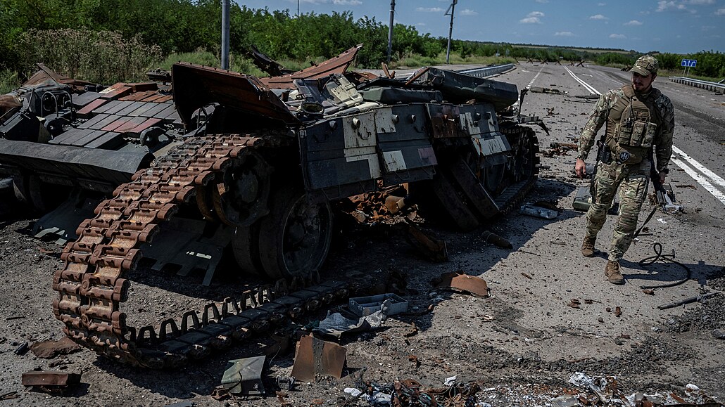 Ukrajinský voják prochází kolem znieného ukrajinského tanku nedaleko obce...