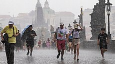 Lidé procházejí po Karlově mostě při bouřce. (10. července 2023)