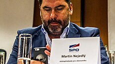 Konference strany SPO. Martin Nejedlý píše na telefonu s podobiznou Vladimíra...