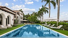 Upravený pozemek je lemovaný vysokými palmami, obklopujícími velkolepý bazénový...
