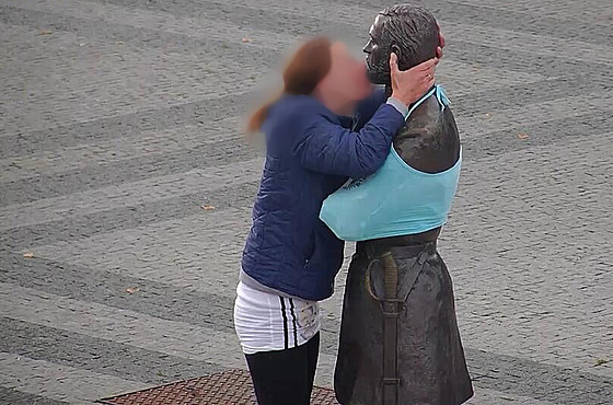 ena bez domova líbá sochu Jana Pernera. Ped tím vykonala potebu na nedalekém...