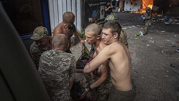 Ukrajinští vojáci po ruském raketovém útoku na město Kosťantynivka nesou do sanitky vážně zraněnou ženu. (6. září 2023)