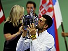 Srbský tenista Novak Djokovi líbá trofej pro vítze US Open.