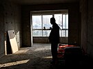 Li Pengfei stojí u postele ve svém byt v nedokonené obytné budov komplexu...