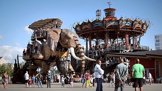 Turisté na mechanickém slonovi vyrobeném z oceli a dřeva v bývalém přístavišti města Nantes ve Francii. Autorem je francouzský umělec Francois Delaroziere