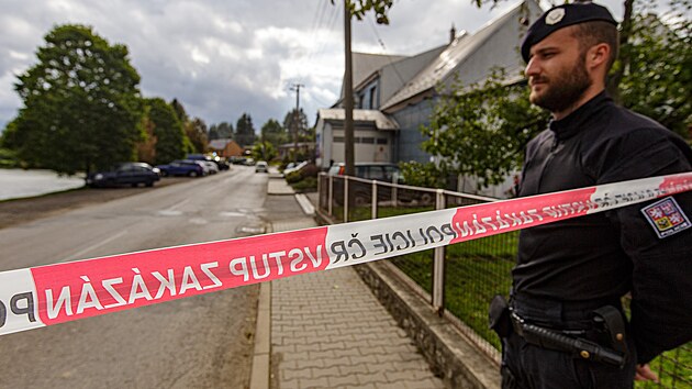 Policista hlídá ulici po výbuchu v domě v Otinovsi.