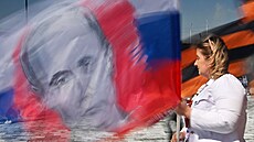 Rusové v májových prvodech mávají vlajkou s prezidentem Vladimirem Putinem....