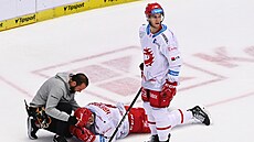 Tinecký Patrik Hrehorák leí na led, stojí u nj spoluhrá Milo Roman.