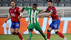 Mihlali Mayambela (uprost�ed) z Arisu Limassol brán�ný Nicolasem Raskinem...