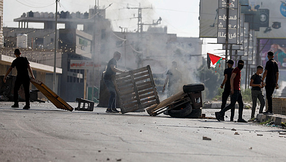 Palestinci kráčejí kolem ohně během protestu ve městě Náblus po izraelských...