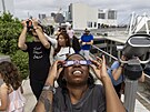 Lidé v Miami sledují zatmní Slunce. (14. íjna 2023)