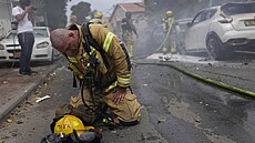 Izraelský hasi kleí v Akelonu na kolenou poté, co se svými kolegy hasil auta...