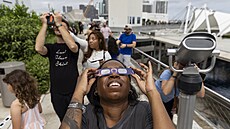 Lidé v Miami sledují zatmní Slunce. (14. íjna 2023)