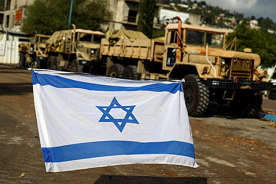 Izraelská vlajka visí na drát v míst, kde se shromaují vojenská vozidla....