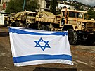 Izraelská vlajka visí na drát v míst, kde se shromaují vojenská vozidla....