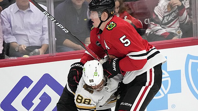David Pastrňák (88) z Boston Bruins dostává v zápase s Chicago Blackhawks ránu od Connora Murphyho.
