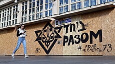 ena prochází kolem graffiti s ukrajinským státním znakem a Davidovou hvzdou s...