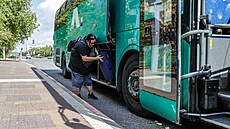 �ena nakládá své zavazadlo do autobusu, kdy� se v rámci evakuace p�ipravuje na...