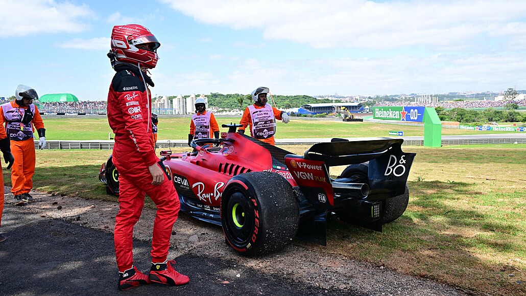 Charles Leclerc prochází kolem svého odstaveného Ferrari.
