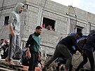 Palestinci prohledávají trosky zícené budovy a hledají peiví a obti...