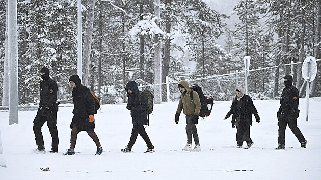 Finsk pohranin str doprovz migranty pichzejc na hranin pechod Raja-Jooseppi ve finskm Inari. (25. listopadu 2023)