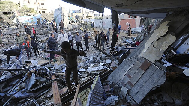 Palestinci stoj u budovy znien pi nonm izraelskm bombardovn v Rafhu v psmu Gazy. (24. listopadu 2023)
