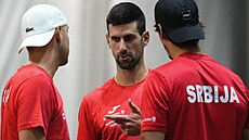 Srbský tenista Novak Djokovi debatuje se spoluhrái na tréninku ped zápasem s...