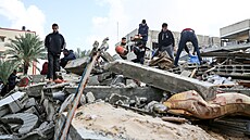 Palestinci prohledávají trosky zícené budovy a hledají peiví a obti...