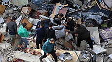 Palestinci prohledávají trosky zícené budovy a hledají peiví a obti...