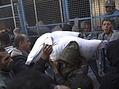 Muž nese pytle s moukou, zatímco se Palestinci shromažďují před distribučním...