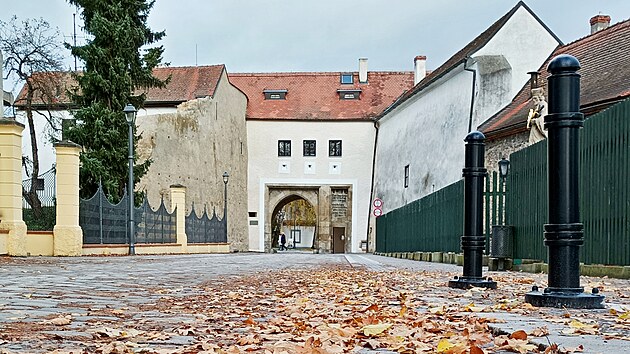 Novohradskou branou přicházejí lidé od rybníka Svět do historického jádra Třeboně. Vedle ní stojí pivovar Regent.