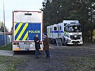 Speciální policejní kamiony u vstupu do lesa, kde probíhá bezpenostn pátrací...