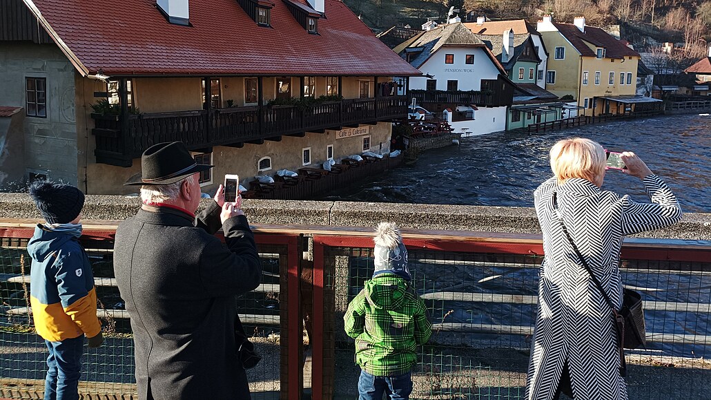 Rozvodnnou Vltavu si fotí turisté.