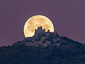 Studený Msíc v úplku zapadá za hradem a vesnicí Rocca Calascio v italském...
