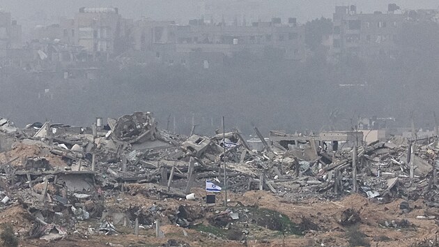Izraelsk vlajky vlaj vedle trosek zniench budov v Gaze. (23. prosince 2023)