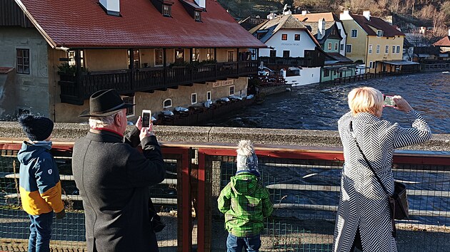 Rozvodnnou Vltavu si fotí turisté.